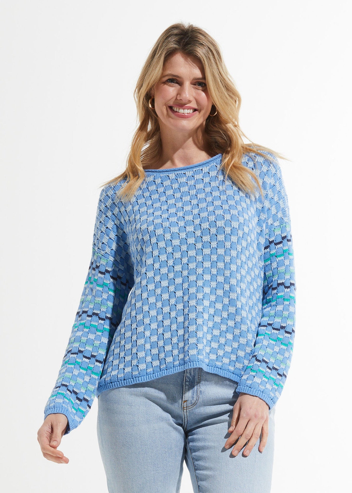 Woman wearing a blue patterned sweater and jeans on a white background