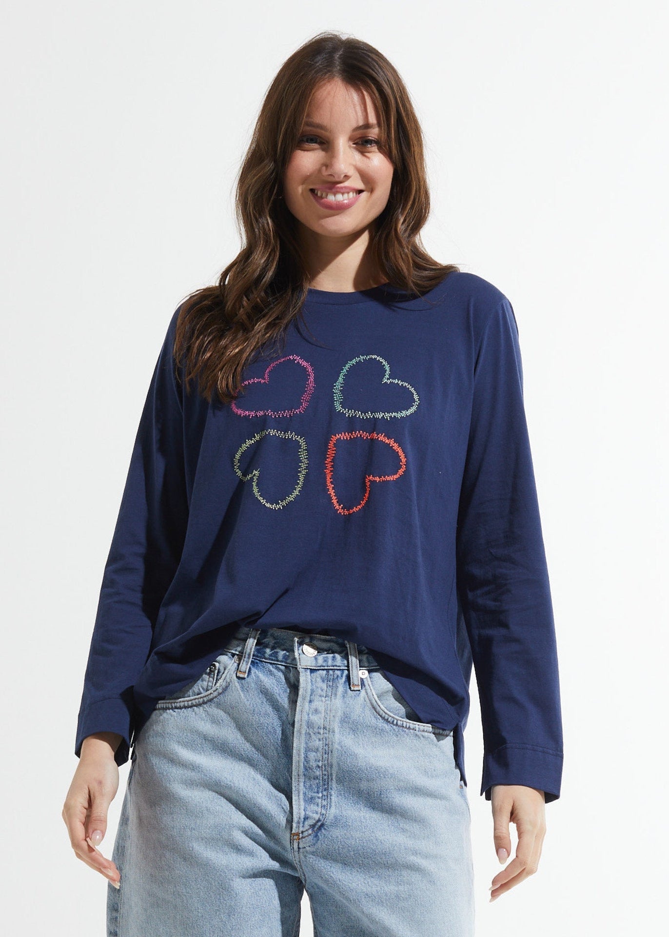 Woman wearing a navy blue sweatshirt with colorful cloud design on a plain background